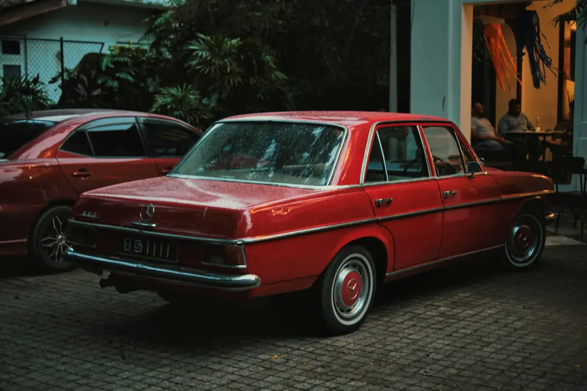 A red classic car is parked outside.